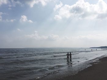 Silhouette men at beach against sky