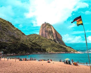 People at beach against cloudy sky