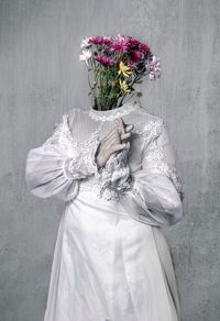 Portrait of woman standing against white wall