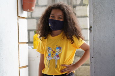 Portrait of woman standing against yellow wall