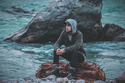 Man sitting on rock by sea