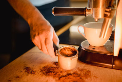 Cropped image of man holding coffee on table