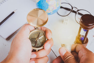 Cropped image of person holding illuminated light bulb and compass