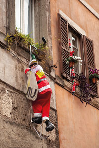 Decor in form of santa claus hangs on wall of house. funny traditional christmas decoration, toy 