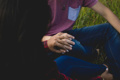 High angle view of couple holding hands while sitting on field