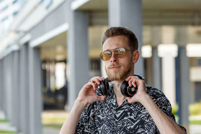 Portrait of a young man in sunglasses and headphones against the background of a modern city