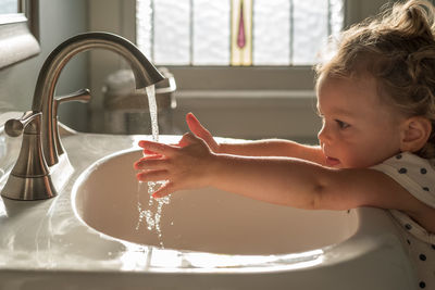 Close-up of cute girl playing with water at sink