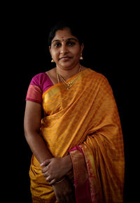 Portrait of woman in sari standing over black background