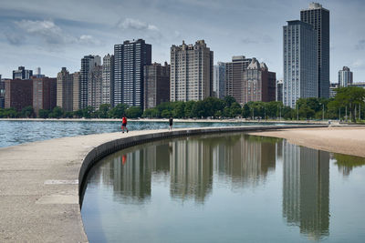 Reflection of buildings in city against sky