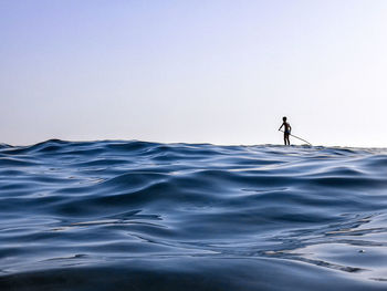 Silhouette man surfing in sea against clear sky