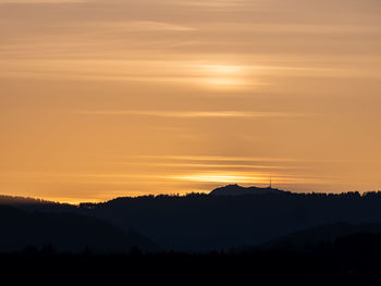 Scenic view of silhouette mountains against orange sky