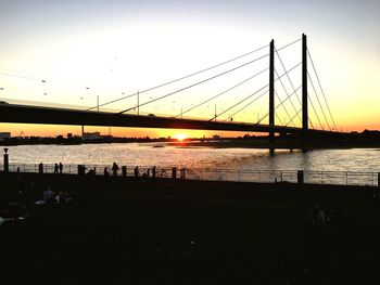 Silhouette of bridge over river at sunset