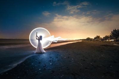 Lamp post on beach against sky during sunset