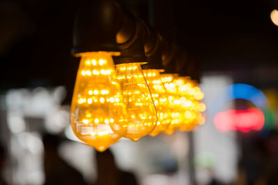 Close-up of illuminated lighting equipment hanging at night