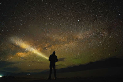 Rear view of silhouette woman standing against star field at night