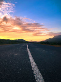 Surface level of road against sky during sunset