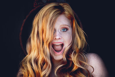 Portrait of beautiful young woman against black background