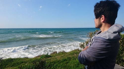 Side view of man looking at sea against sky