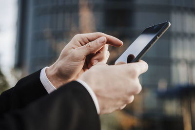 Close-up of businessman using smart phone outdoors