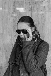 Portrait of man wearing sunglasses standing against wall