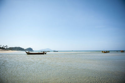 Boats sailing in sea against clear sky