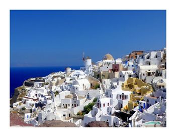 Townscape by sea against clear blue sky