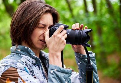 Woman photographing through camera outdoors