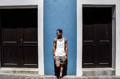 Young man standing against door