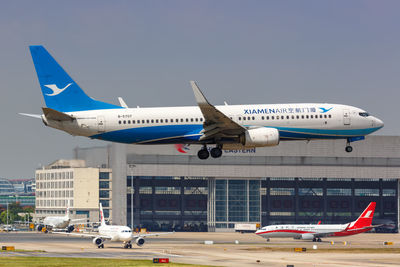 Airplane flying over airport runway against sky