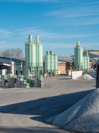 Outdoor space of a glass factory with vertical tanks and selected glass materials stacked together.