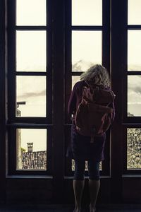Rear view of woman standing against window