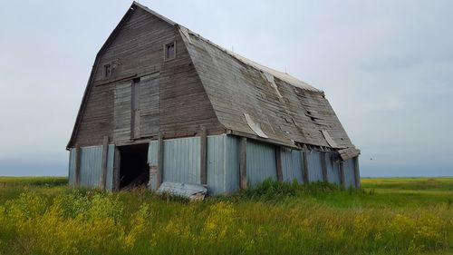 Abandoned barn on field against sky