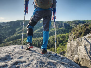 Man with crutches and strong will. disabled tourist successfully climb in park. hurt hiker man