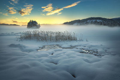 Scenic view of frozen lake against sky during sunset