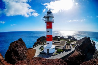 Lighthouse by sea against sky