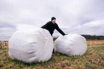 Man standing by haystack on field