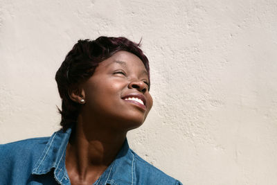 Portrait of smiling young woman standing against wall