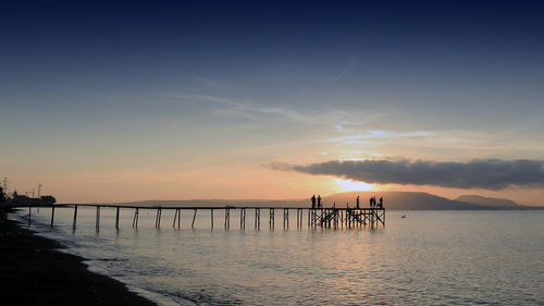 Silhouette pier over sea against sky during sunset