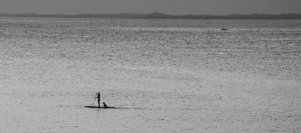 Distant view of man sailing boat in sea