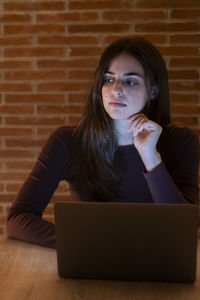 Young woman using laptop while sitting on sofa at home