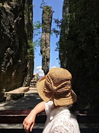 Side view of woman standing by rock formation against trees