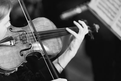 High angle view of mid adult woman playing violin while sitting indoors