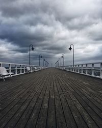 Pier on river against cloudy sky