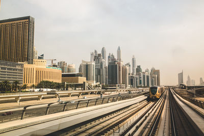 Railroad tracks in city against sky