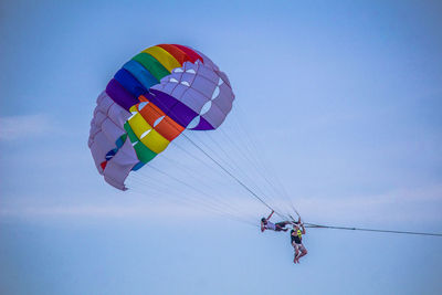 Low angle view of friends parasailing against sky