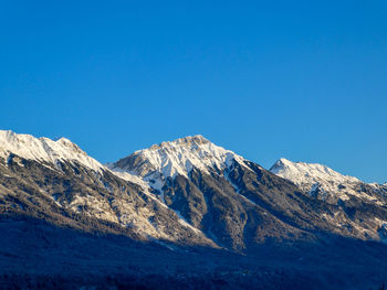 Scenic view of snowcapped mountains against clear blue sky