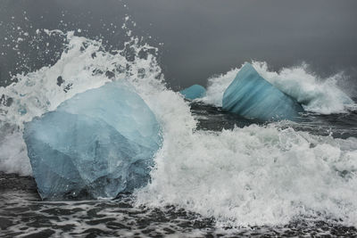 Waves splashing on icebergs in sea