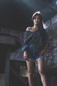 Portrait of beautiful young woman standing against wall