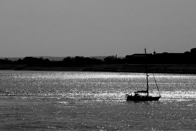Silhouette sailboats in sea against clear sky