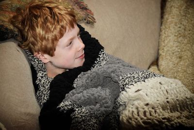 High angle view of little boy resting in knitted blanket